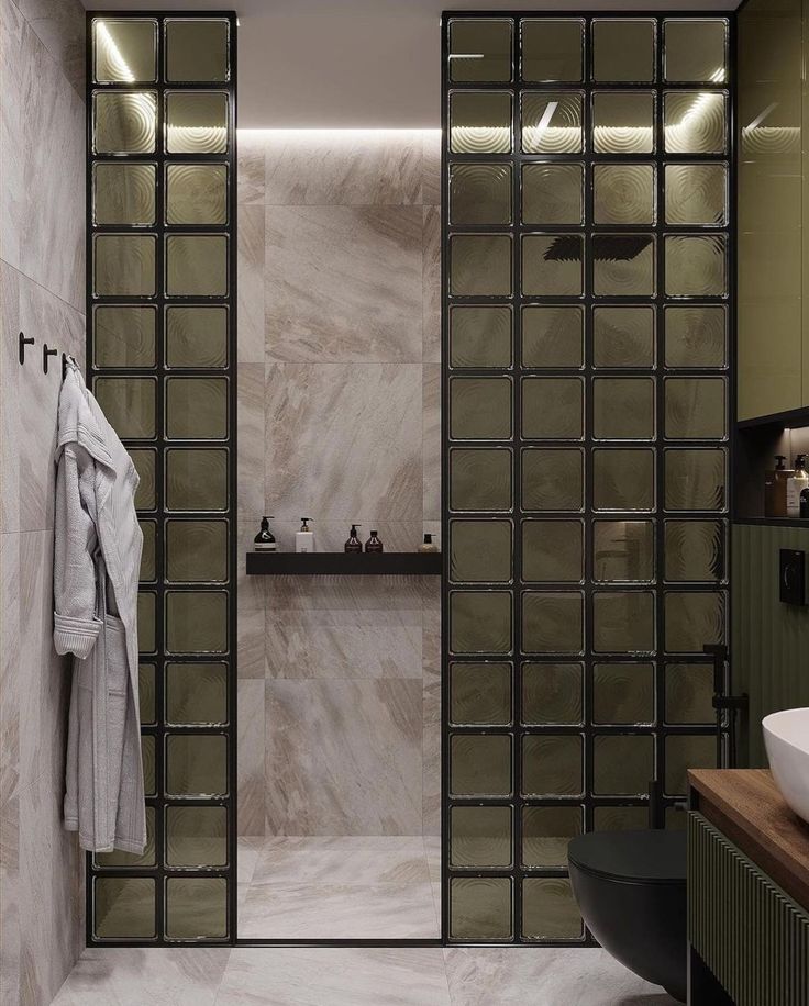 a bathroom with a glass shower door and marble walls, along with a white sink