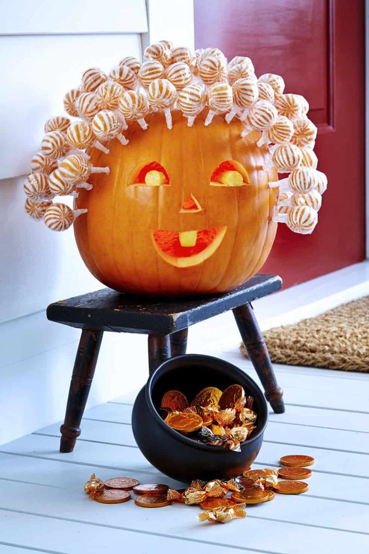 a pumpkin sitting on top of a chair next to a bowl filled with candy chips