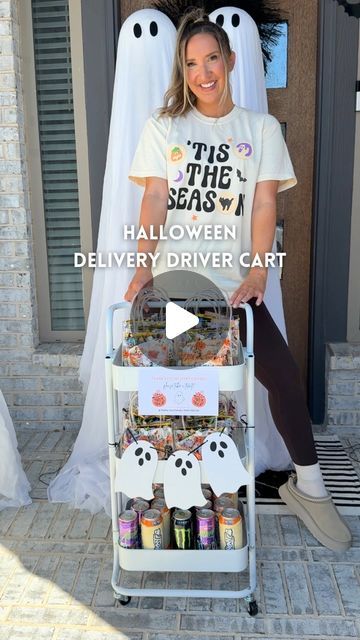 a woman sitting on top of a cart filled with halloween treats next to ghost decorations