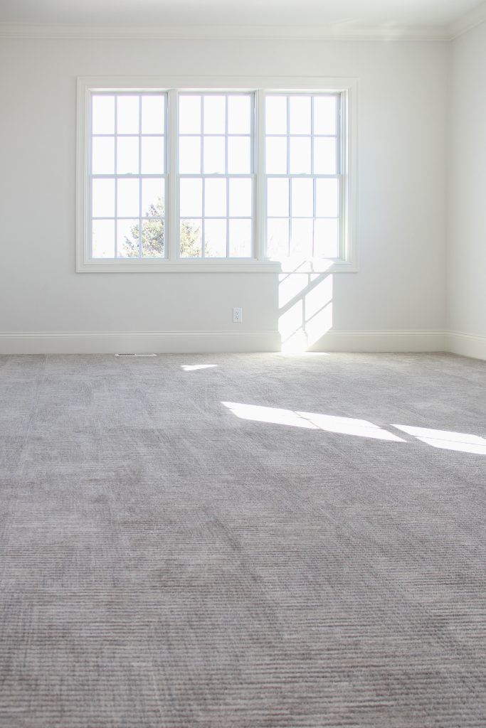 an empty room with no one in it and the light coming through the window is shining on the carpet