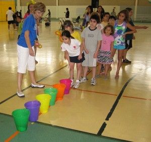 a group of young children standing on top of a gym floor next to plastic cups