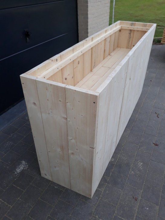 a large wooden box sitting on top of a brick floor next to a garage door