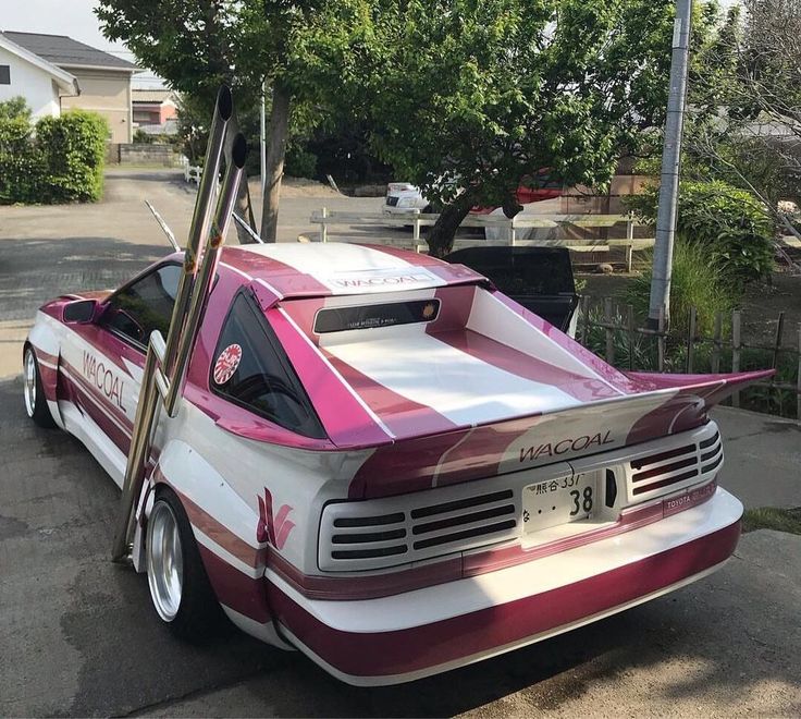 a pink and white car is parked on the street