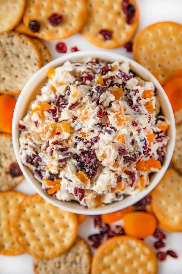 a white bowl filled with cheese and crackers on top of a table next to crackers