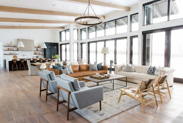 a living room filled with lots of furniture and large windows in the wall behind it