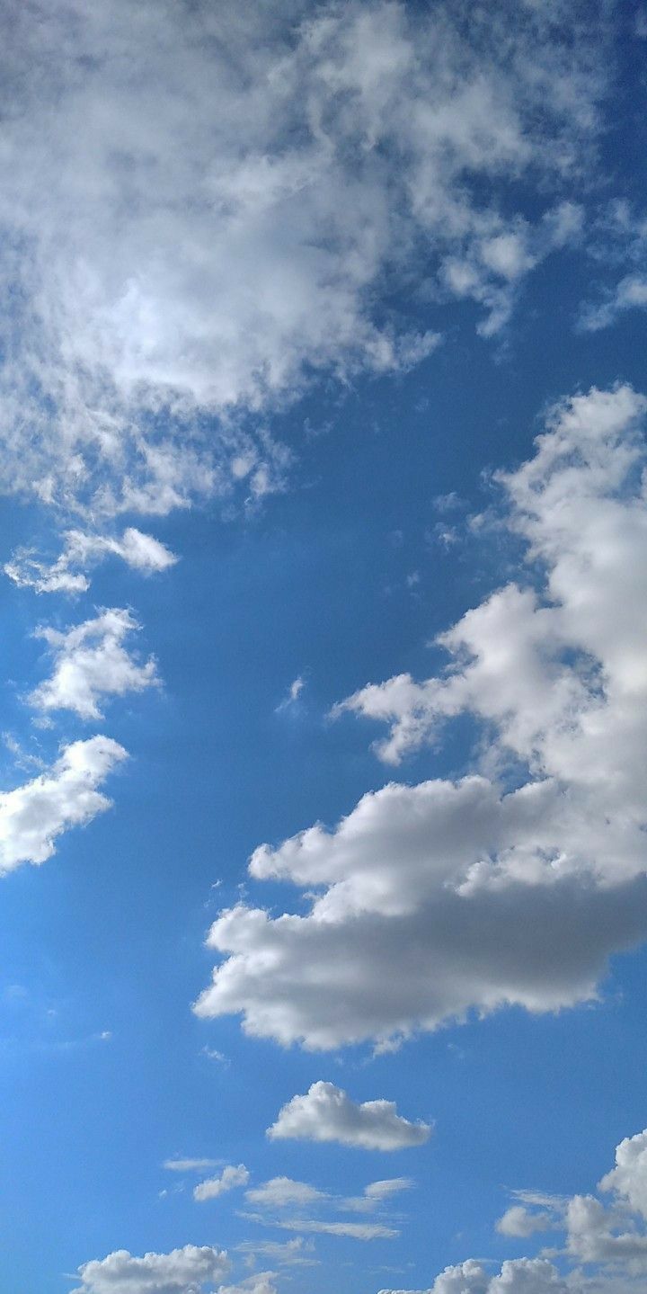 the airplane is flying high in the blue sky with white clouds above it and below