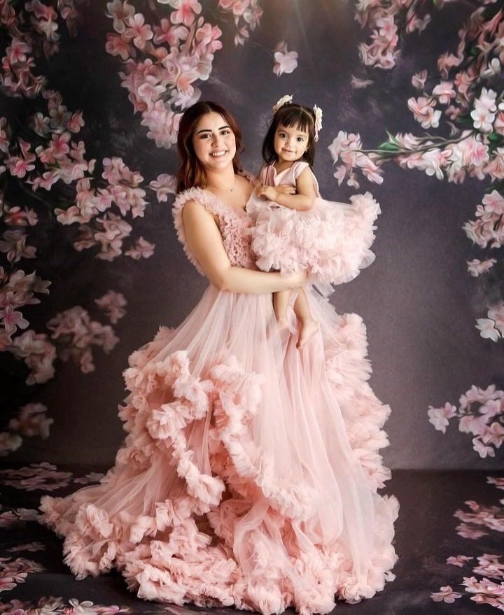 a woman in a pink dress holding a small child wearing a flowered headband