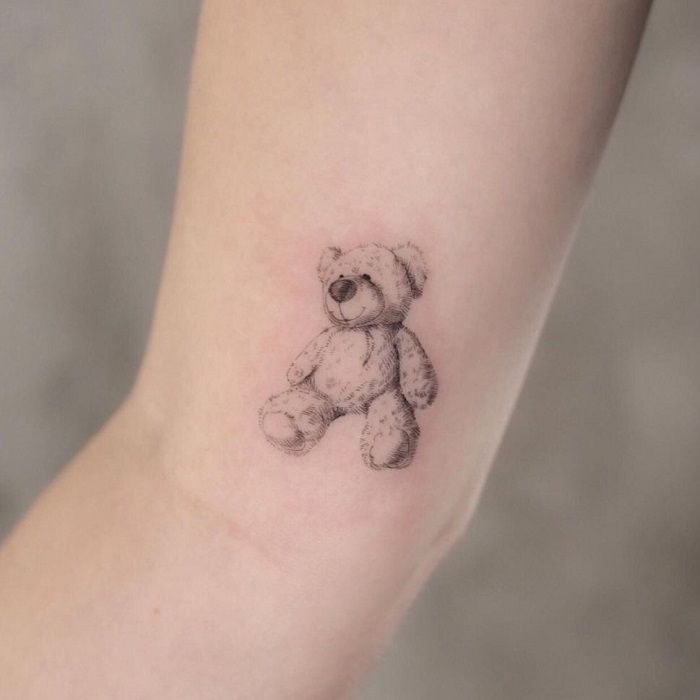 a small teddy bear tattoo on the arm