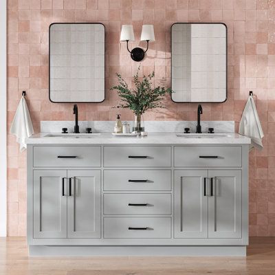 a bathroom with two sinks and mirrors on the wall next to each other in front of a pink tiled wall