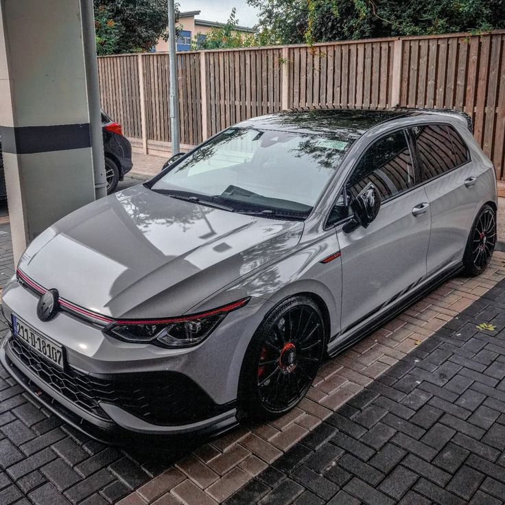 a grey car parked next to a wooden fence