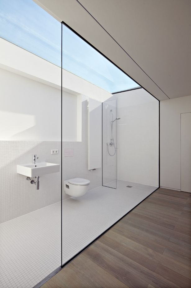 a white bathroom with glass walls and wood flooring