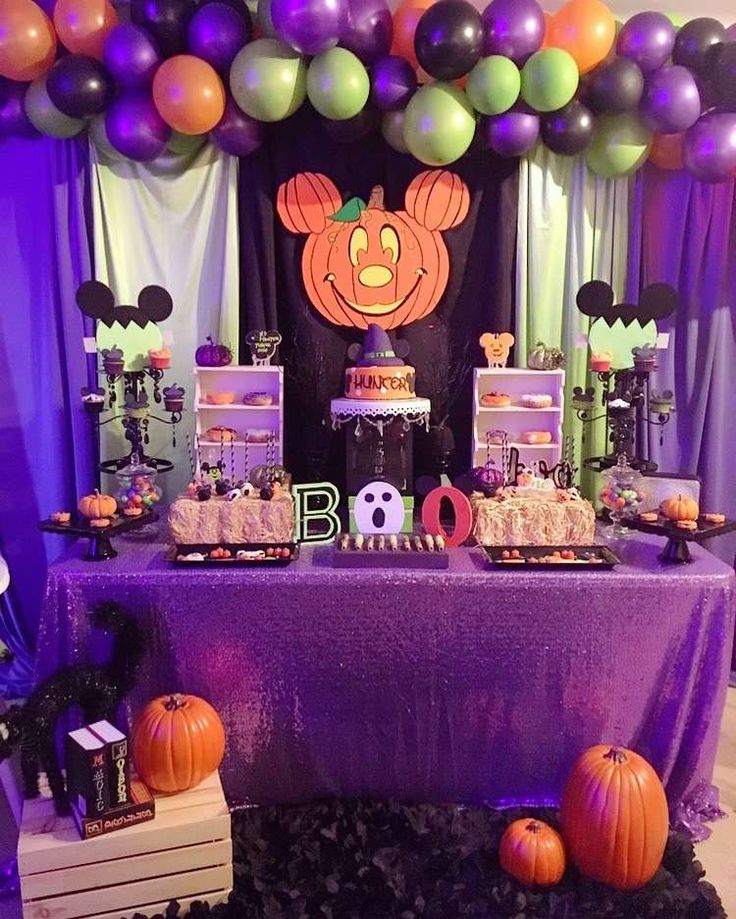 a purple table topped with lots of cake and desserts next to balloon arches filled with balloons