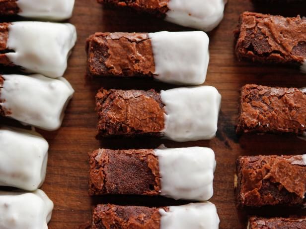 chocolate brownies with white icing are on a wooden board and ready to be eaten