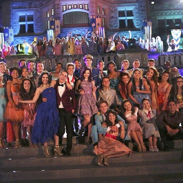 a group of people posing on steps in front of an old building at night time