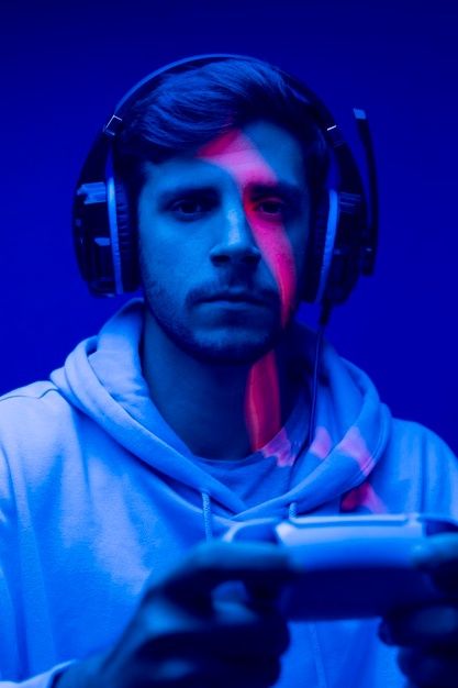 a man wearing headphones and holding a controller in front of his face with red light