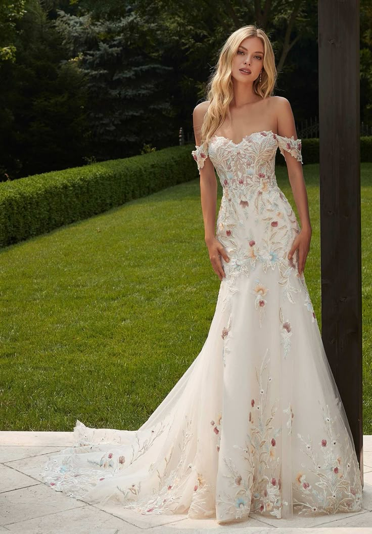 a woman in a wedding dress posing for the camera on a stone walkway with grass and bushes behind her