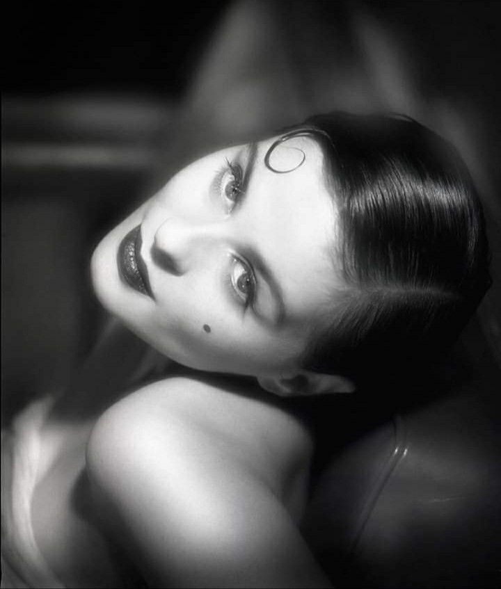 a black and white photo of a woman with her eyes closed, looking at the camera