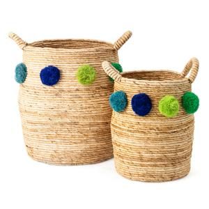 two woven baskets with pom - poms on the handles, one is blue and green