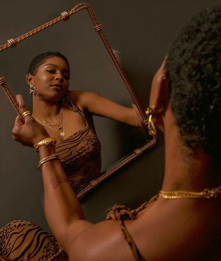 a woman is looking at herself in the mirror while wearing gold jewelry and bracelets