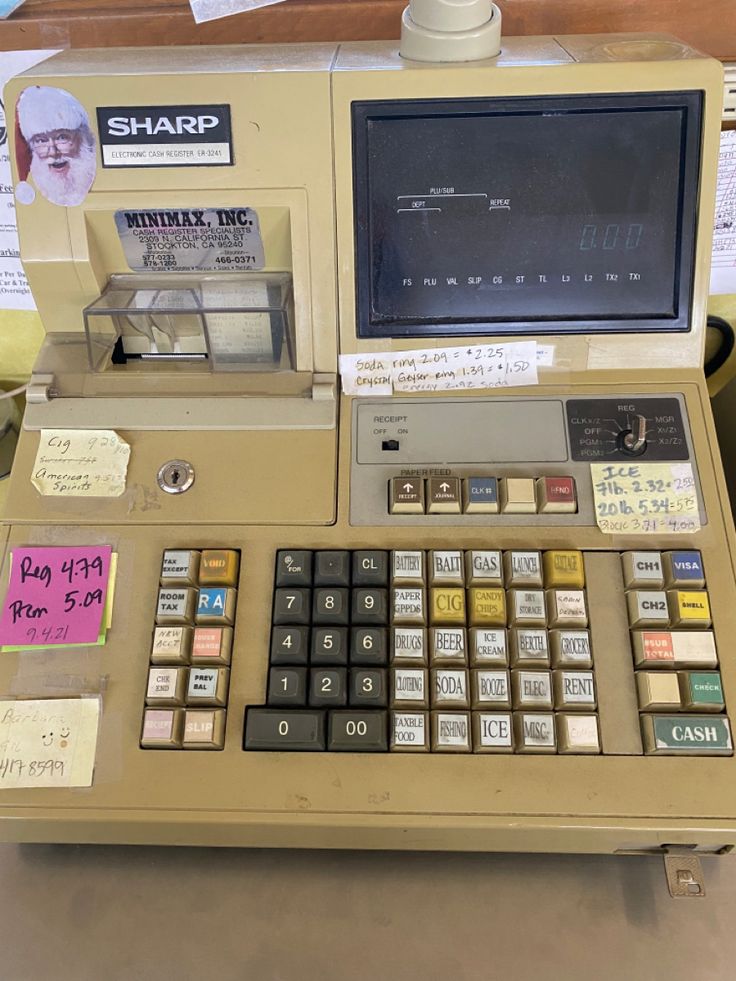 an old cash register machine with lots of stickers on it