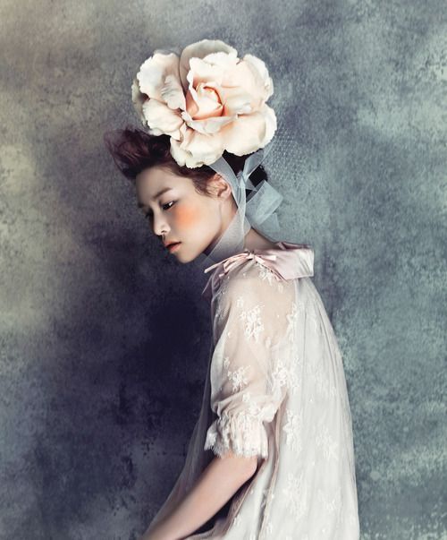 a woman with a flower in her hair wearing a white dress and holding a purse