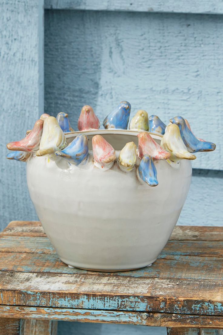 small ceramic birds sitting in a bowl on top of a wooden table next to a blue door