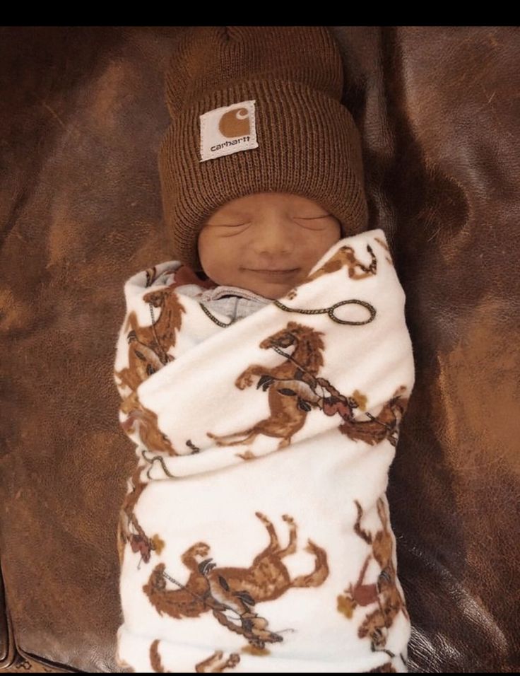 a baby wrapped in a blanket and wearing a hat