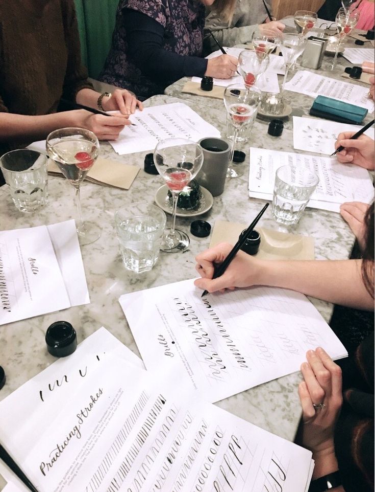 a group of people sitting around a table with papers and wine glasses on top of it