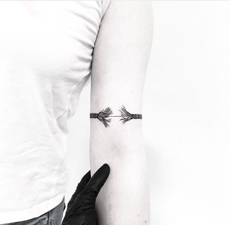 a woman's arm with an arrow tattoo on the left side of her arm