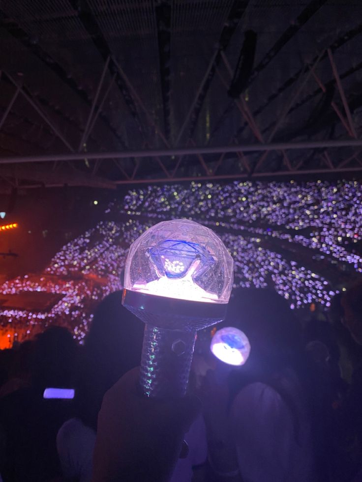 a person is holding up a light in front of a stage with lights on it