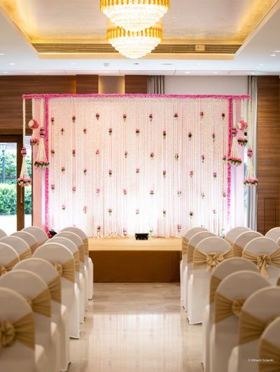 the ceremony room is set up with white chairs and pink sashes on the wall