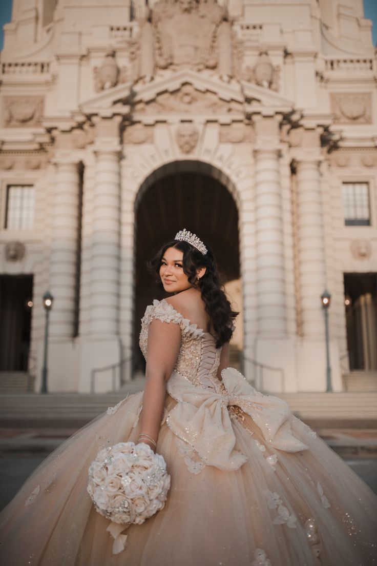 a woman in a wedding dress is posing for the camera with her bouquet and tiara