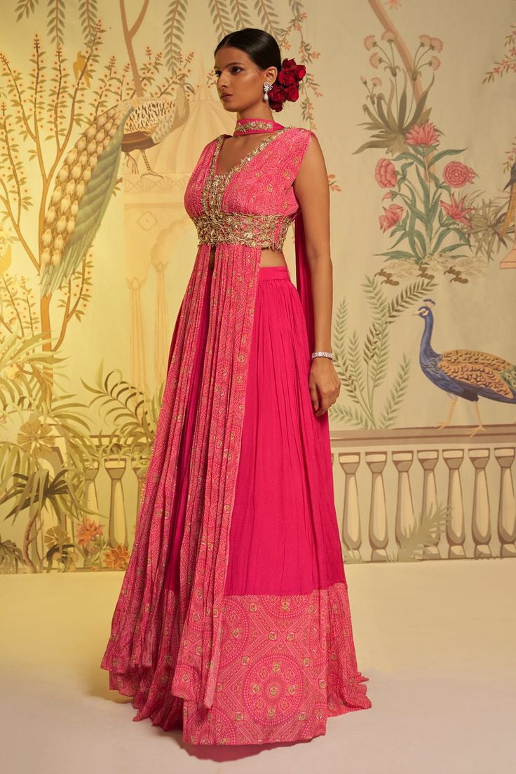 Rani pink anarkali style padded blouse with bandhani print and embroidered neckline. Paired with pleated lehenga with attached cancan and stole dupatta.
Component: 3
Pattern: Printed
Type Of Work: Bandhani
Neckline: V neck
Sleeve Type: Sleeveless
Fabric: Lehenga and Stole Dupatta: Georgette Crepe, Blouse: Crepe Silk
Color: Pink
Other Details: 
Embroidered dupatta
Closure: Side zipper
Occasion: Destination Wedding - Aza Fashions Bandhani Dress Pattern, Bandhani Anarkali, Bandhani Lehenga, Pleated Lehenga, Floral Anarkali, Bandhani Print, Pink Anarkali, Printed Anarkali, Anarkali Lehenga