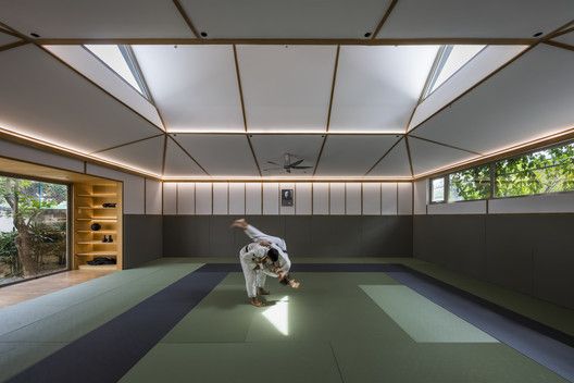 a man practicing karate moves in a room with green and blue flooring on the ground