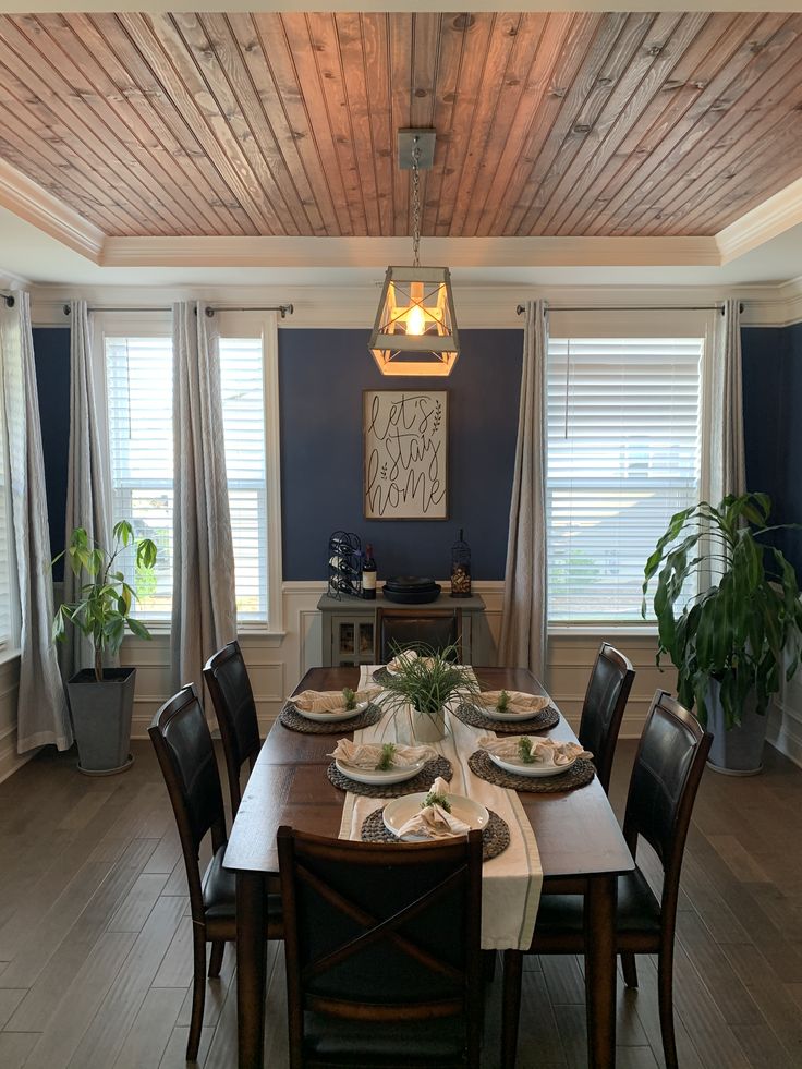 the dining room table is set for four with place settings on each plate, along with two potted plants