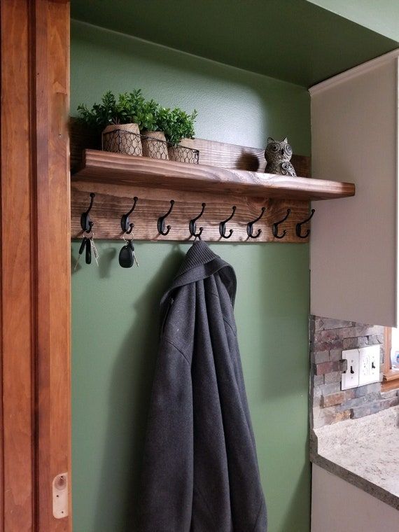 a towel hanging on a shelf above a sink in a green room with potted plants and kitchen utensils