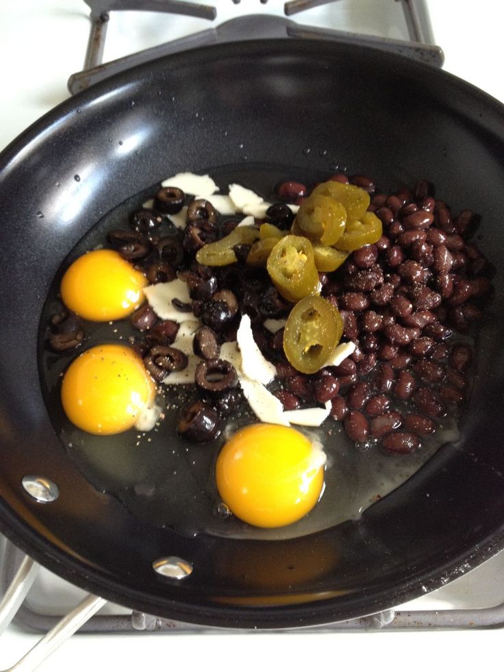 eggs, beans and onions cooking in a pan on the stove