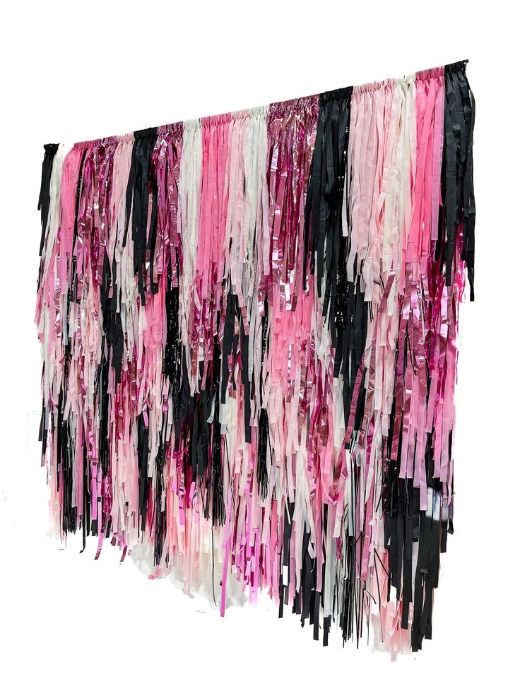 pink, black and white streamers are hanging from the side of a wall in front of a white background