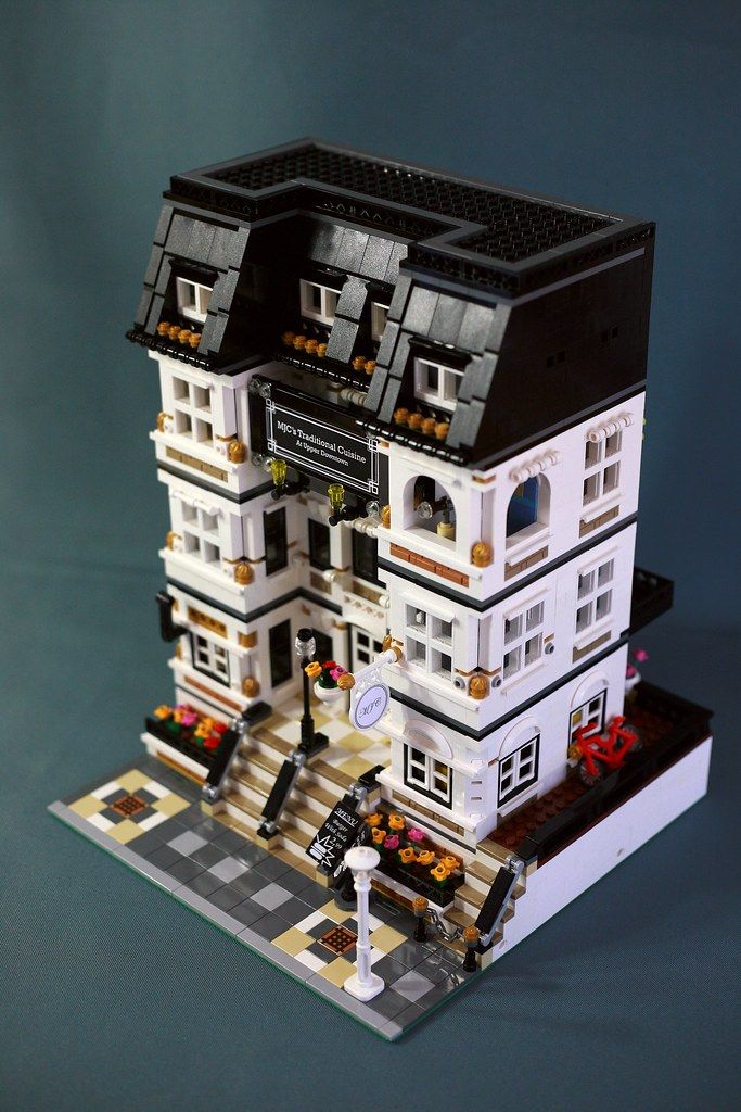 a lego model of a white building with black roof and two stories on the second floor