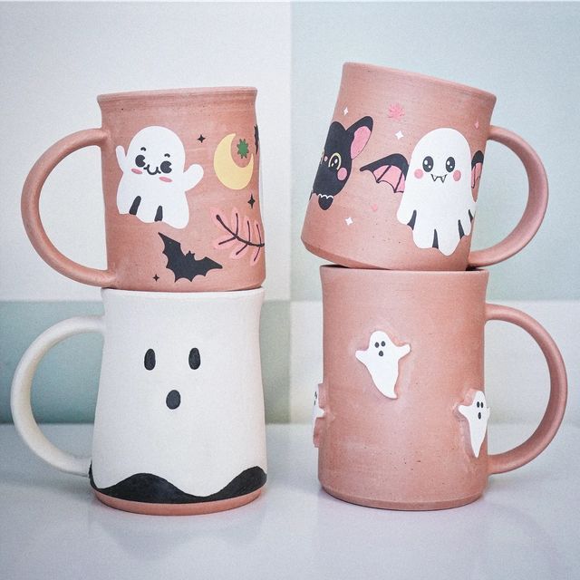 three coffee mugs decorated with halloween images and ghost faces are sitting on a table