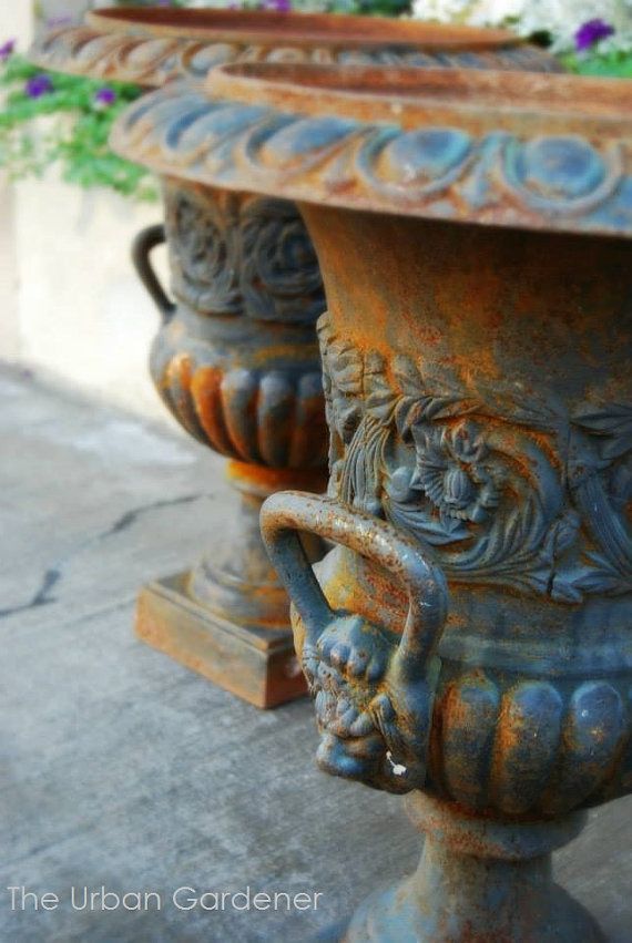 two large vases sitting next to each other on the side of a building with flowers in them