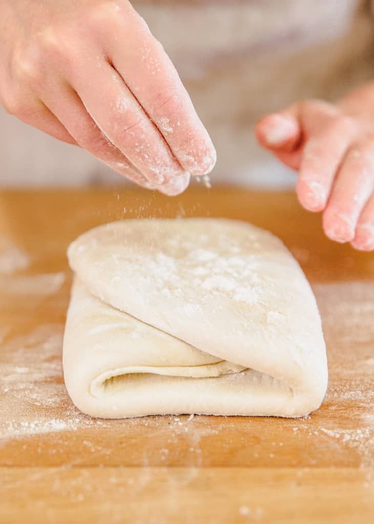 a person kneading dough on top of a wooden table