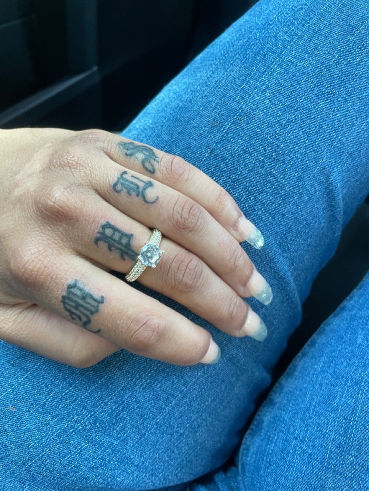 a woman's hand with tattoos on it sitting in the back seat of a car