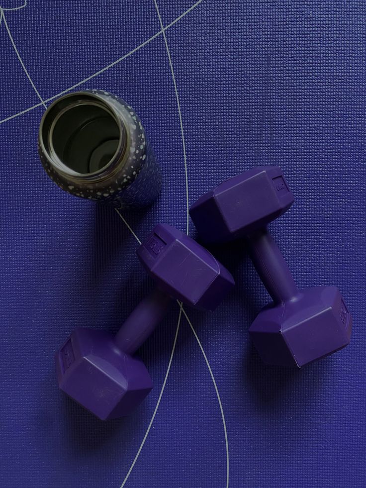 two purple dumbs sitting on top of a blue mat next to a bottle opener