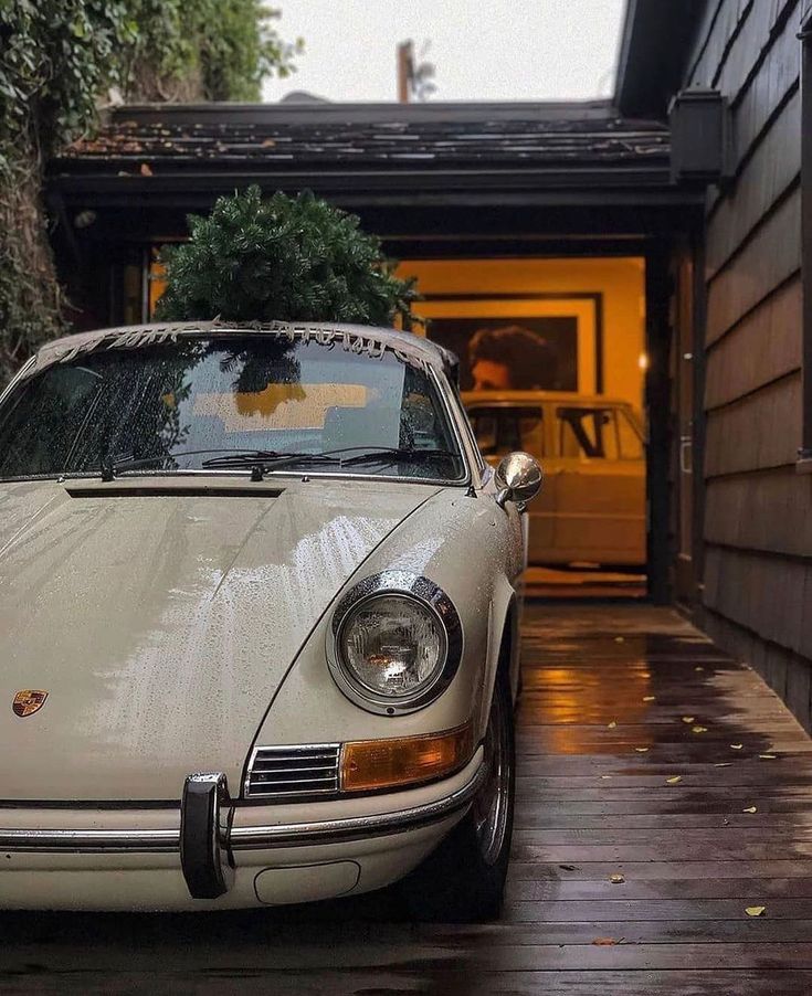 a white car parked in front of a house with a christmas tree on the hood