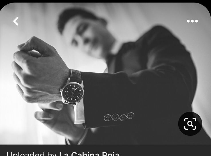 a man in a suit is holding his watch