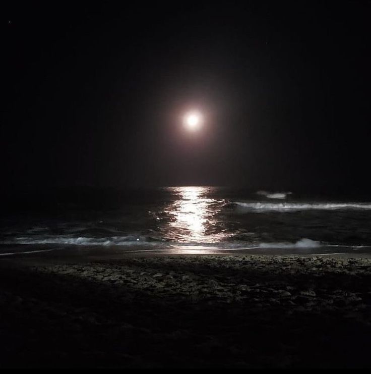 the moon is shining over the ocean at night