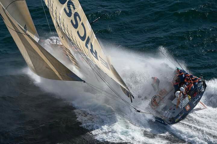 a sailboat with people on it is in the water near another boat that has just taken off