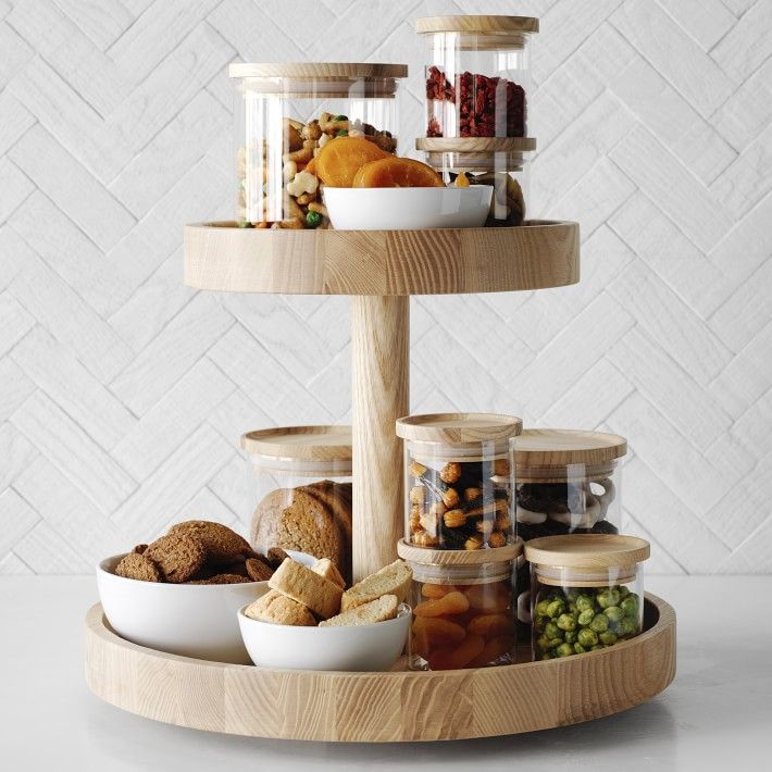 a three tiered wooden tray with food in it