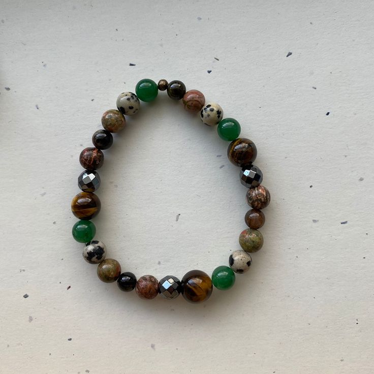 A handcrafted bracelet devoted to the earth element. Made using: Tourmaline- A grounding and protective stone, used to absorb negativity. Unakite- A highly nurturing stone used for healing and emotional centering. Dalmation Jasper- Carries playful energy, and helps connect you with your inner child. Green Aventurine- Brings in good luck, fortune, and prosperity. Tiger's Eye- A fiery stone that boosts confidence, promotes grounding and protection, and uplifts energy. Hematite- The magnetic qualities of this stone make it excellent for grounding and drawing abundance toward you. Leopard Jasper- Used for grounding, stability, connection to the earth, and an increase in confidence. I offer a variety of sizes to choose from, however, if you don't see your size listed, just message me and I'll m Holistic Round Beads Bracelet For Everyday, Holistic Everyday Bracelet With Round Beads, Casual Agate Gemstone Beaded Bracelets, Casual Agate Beaded Bracelets With Gemstone Beads, Brown Gemstone Beads Bracelets For Healing, Spiritual Stretch Bracelet With Natural Stones, Earthy Handmade Stretch Bracelet With Round Beads, Everyday Spiritual Stretch Bracelet With Natural Stones, Earthy Handmade Stretch Bracelet